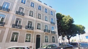 Un immeuble à plusieurs étages, doté d’une façade ornée, de balcons et de voitures garées devant.