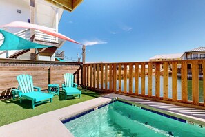 A pool area with a wooden fence, a small pool, and blue chairs. - Private Heated Pool, Golf Cart Included, Boardwalk to the Beach (Port Aransas)