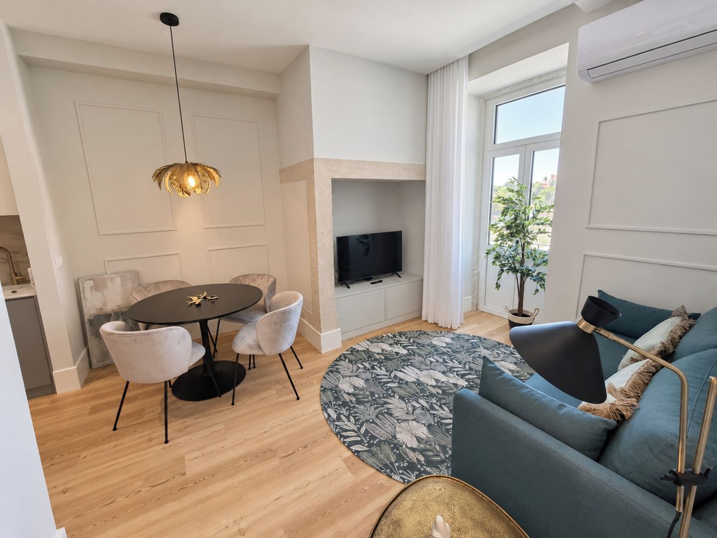 A modern living room with a round dining table, sofa, and a flat-screen TV.
