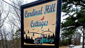 Skilt for Cardinal Hill Cottages med en vintage lastbil og illustration af en fugl.
