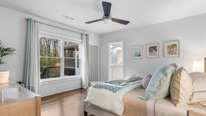 Une chambre à coucher avec un lit, un bureau, un ventilateur de plafond et une fenêtre avec des rideaux.