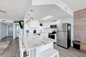 A modern kitchen with white cabinetry, stainless steel appliances, and a marble countertop.