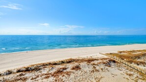 A beach with a wooden boardwalk leading to the water, sandy dunes, and a clear blue sky. - Beachfront 1BR @ Phoenix X • Sleeps 4 • Gulf Views & Next to Flora-Bama (Orange Beach)