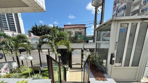 A hotel entrance with a tiled floor, a glass door with a wheelchair accessibility sign, and a staircase leading to the entrance. - Flat Jardins da Madalena (Recife)