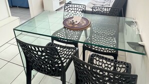 A modern dining area with a glass table, black chairs, and pendant lights. - Flat Jardins da Madalena (Recife)