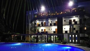 Un hotel de varios pisos con una piscina en primer plano.
