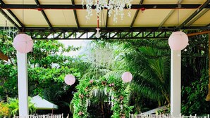 An outdoor event space with a green artificial turf aisle, white chairs on either side, and floral decorations. - Alzurich Private Resort (Dauin)