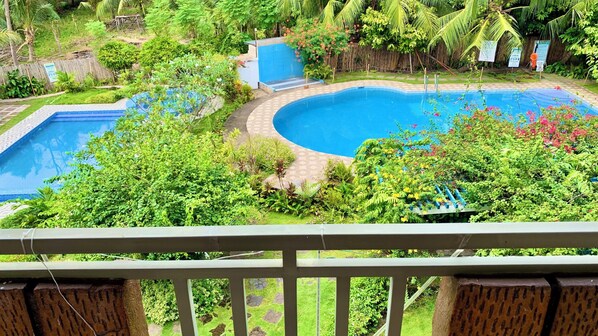A pool surrounded by lush greenery and a wooden deck. - Alzurich Private Resort (Dauin)