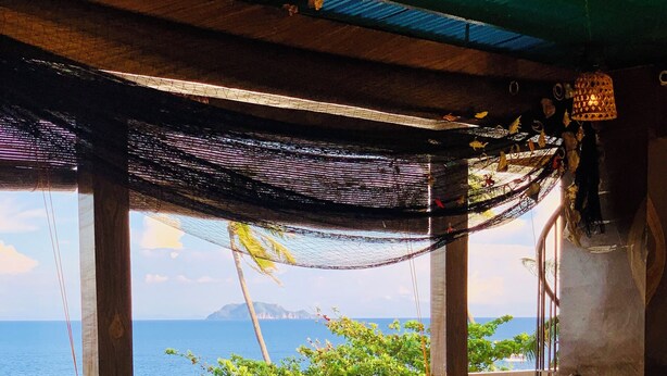 Una mesa y sillas de madera en una habitación con vista al mar.