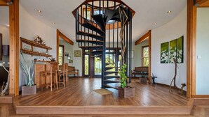 Une pièce spacieuse dotée d’un escalier en colimaçon, de planchers en bois et d’un coin repas avec des chaises et une table.