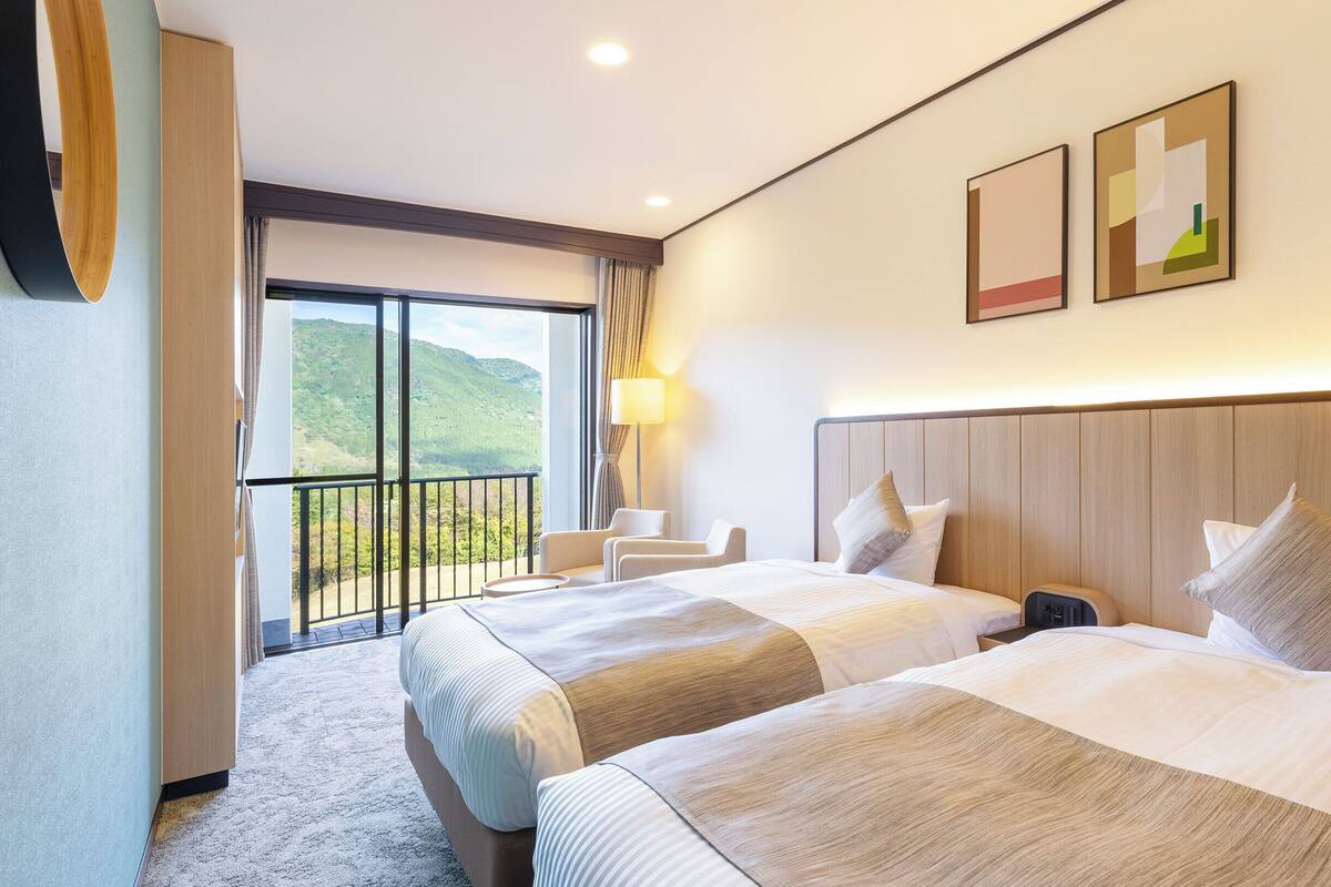 Una habitación de hotel con dos camas, un balcón, un escritorio y una silla.