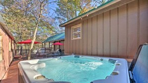 Un espace avec un bain à remous, une terrasse en bois, des sièges d’extérieur et un patio couvert agrémenté de parasols rouges.