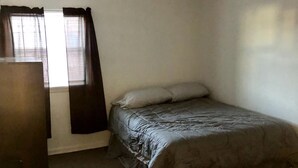 A bedroom with a bed, a ceiling fan, a window with curtains, and a dresser.