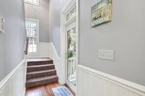 A hallway with a wooden floor, white wainscoting, and a door with a glass panel. - Beach Days Made Simple, Memories Made Easy | Heated Pool Access (Tybee Island)
