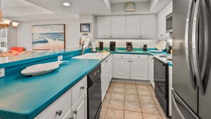 Een moderne keuken met witte kastjes, een blauw aanrechtblad en een roestvrijstalen koelkast.