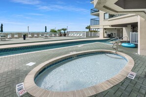 A pool area with a hot tub, lounge chairs, and a view of the ocean. - Ocean Bay Club 107 | Oceanfront 4BR Condo | Steps to Main St & Beachfront Pool (North Myrtle Beach)