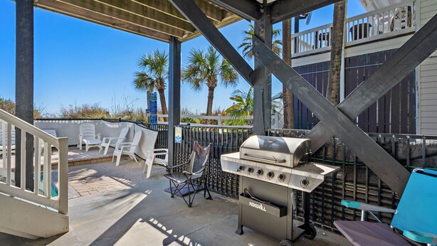 Patio esterno con barbecue, sedie e area piscina.