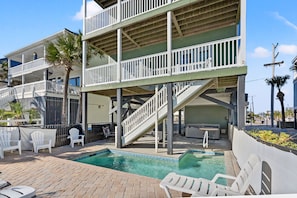 A multi-story building with a pool area, including a staircase, lounge chairs, and a hot tub. - Oceanfront vacation rental with pool, hot tub, and game room—perfect for families and groups (North Myrtle Beach)