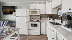 A modern kitchen with white cabinetry, a microwave, a kettle, and a coffee maker. - Direct oceanfront luxury on the 1st floor—step from balcony to beach in seconds (North Myrtle Beach)