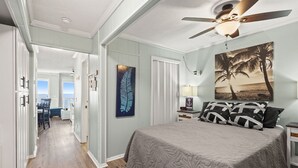 A bedroom with a bed, a nightstand, a ceiling fan, a painting, and a view of the ocean through a door. - Direct oceanfront luxury on the 1st floor—step from balcony to beach in seconds (North Myrtle Beach)