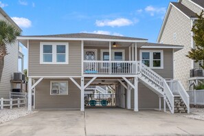 A two-story house with a balcony, a covered porch, and a staircase leading to the upper level. - Family Beach Retreat with Private Pool, Sunset Views, & Cherry Grove Nature Trails by the Coast (North Myrtle Beach)
