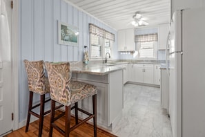 A kitchen with white cabinets, a marble countertop, and a wooden floor. - Family Beach Retreat with Private Pool, Sunset Views, & Cherry Grove Nature Trails by the Coast (North Myrtle Beach)