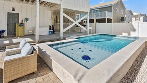 A rectangular swimming pool with a tiled deck, surrounded by a white deck area with wicker furniture. - Exceptional luxury retreat steps from the beach with outdoor oasis, heated pool, elevator (North Myrtle Beach)