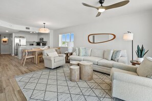 A modern living space with a kitchen, dining area, and seating area, featuring a ceiling fan, pendant lighting, and a large mirror. - Oceanfront condo w/pool, lazy river, & family fun steps from the beach (North Myrtle Beach)