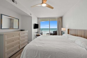 A hotel room with a bed, a dresser, a TV, a balcony with a view of the beach, and a ceiling fan. - Oceanfront condo w/pool, lazy river, & family fun steps from the beach (North Myrtle Beach)
