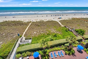 A beach resort with a boardwalk, lounge chairs, and a view of the ocean. - Oceanfront condo w/pool, lazy river, & family fun steps from the beach (North Myrtle Beach)