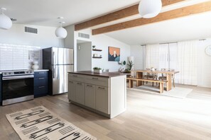 A modern kitchen with a central island, built-in appliances, and a dining area with a wooden table and chairs. - Tucson Spring Escape | Stylish 3BR w/ Sunny Vibes (Tucson)
