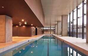 Ein Hallenbad mit gefliesten Wänden und freiem Blick auf den Poolbereich.