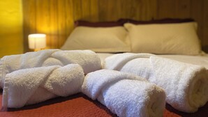 Cama bem arrumada com lençóis brancos e almofada vermelha.
