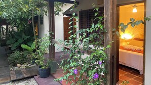 Quarto em estilo japonês tradicional, com tatames, teto de madeira baixo e porta deslizante para uma varanda.