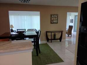 Un comedor con una mesa y sillas, una mesita auxiliar y una alfombra verde.