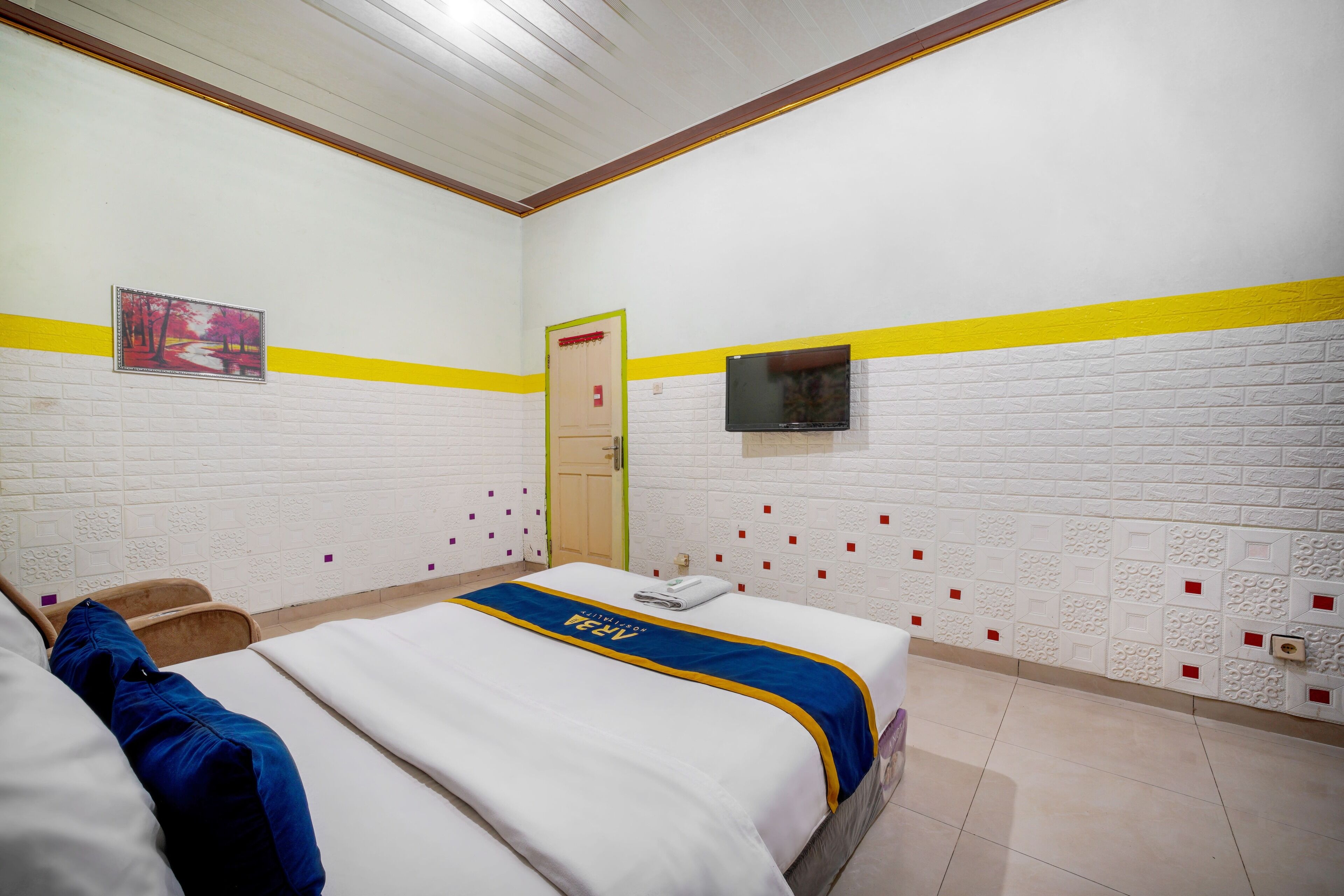 A hotel room with a bed, a television, and a door.