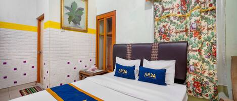 Una habitación de hotel con una cama, una mesita de noche, un espejo y una cortina estampada con motivos florales.