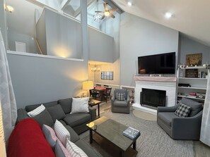 A modern living room with a grey sofa, a coffee table, and a fireplace. - R1 Renovated ski-in ski-out condo in Bretton Woods with fireplace (Bretton Woods)