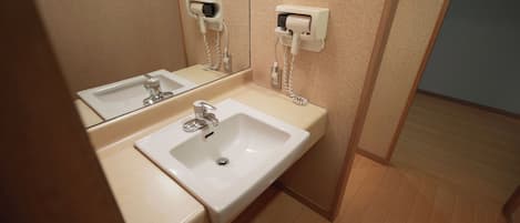 A bathroom with two sinks, a mirror, and a hairdryer mounted on the wall.