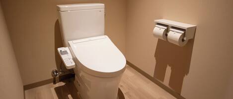 Un baño moderno con inodoro, dispensador de papel higiénico y panel de control.