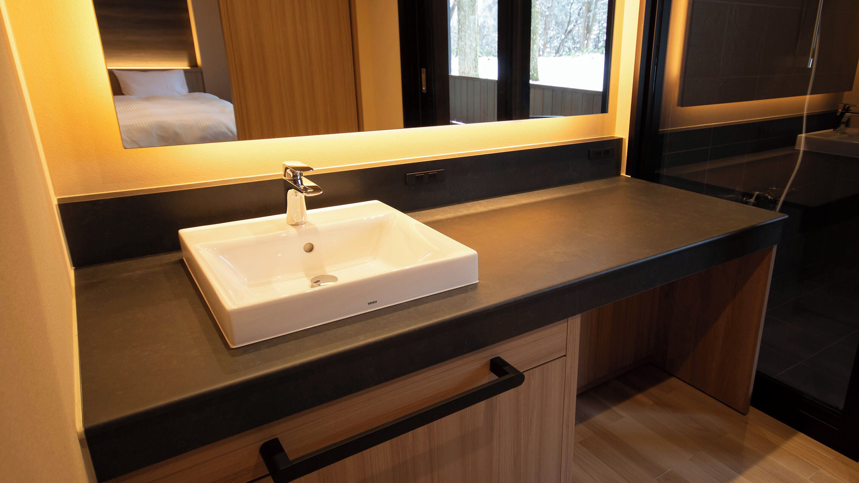 Un baño moderno con un lavabo blanco, un espejo y un armario de madera.