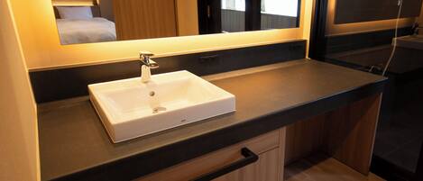 Un baño moderno con un lavabo blanco, un espejo y un armario de madera.