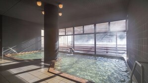 Een binnenzwembad met helder water, grote ramen en uitzicht op een gebouw.