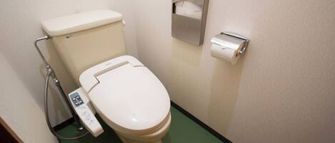 A toilet with a bidet attachment and a paper towel dispenser.