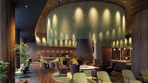 Een moderne zithoek met een gebogen plafond, houten vloeren en diverse zitplaatsen, waaronder fauteuils en banken.