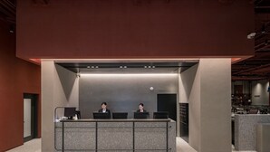 Una recepción con dos empleados, diseño moderno y una cámara de seguridad visible.
