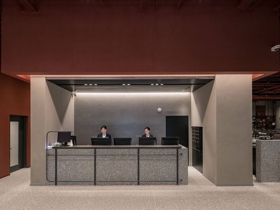 A reception desk with two staff members, a modern design, and a visible security camera.