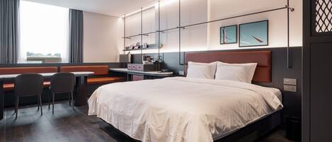 Une chambre d’hôtel moderne dotée d’un grand lit, d’un bureau avec une chaise, d’une fenêtre avec des rideaux et offrant une vue sur l’extérieur.