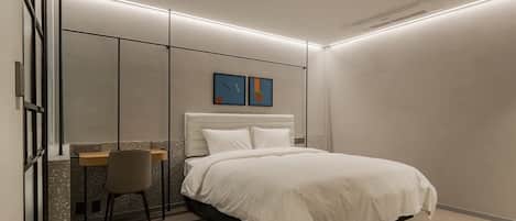 A modern bedroom with a bed, a desk, and a chair.