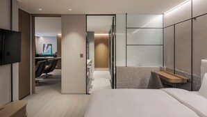 Una habitación de hotel moderna con cama, televisión, escritorio y zona de ducha.